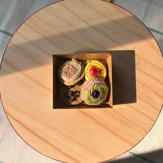 Small box with colorful pastries on a round wooden table